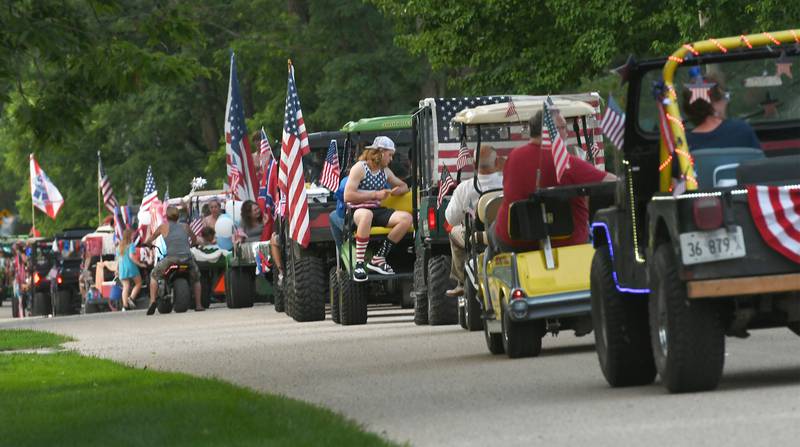 A stream of golf carts and all-terrain vehicles head down a street in Grand Detour during the annual parade.