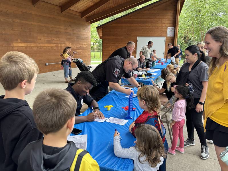 School Resource Officers Justin Martin and Scott Evans sign autographs and play Connect 4 with kids at the 2024 National Night Out.