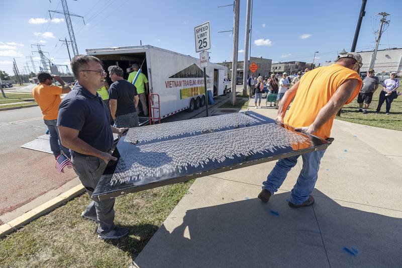 City workers help construct the Vietnam Traveling Memorial Wall Thursday, August 31, 2023 in Rock Falls. When unloading from the truck, the panels with the names are to always face up and to not touch the ground until installation.