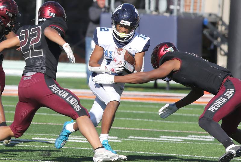 Nazareth's Edward McClain Jr. tries to get by Peoria's Frank Odom and Gary Rutherford during their IHSA Class 5A state championship game Saturday, Nov. 26, 2022, in Memorial Stadium at the University of Illinois in Champaign.