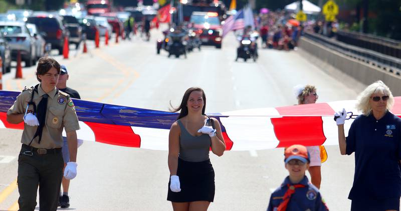 People carry a large flag as part of the Founders’ Days parade along Route 62 in Algonquin Saturday.
