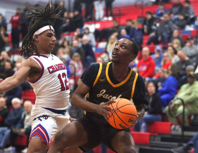 Jacobs’ Elijah Bell, right, moves the ball as Dundee-Crown’s Anthony Spain defends in varsity boys basketball on Friday, Dec. 12, 2025, at Dundee-Crown High School in Carpentersville.