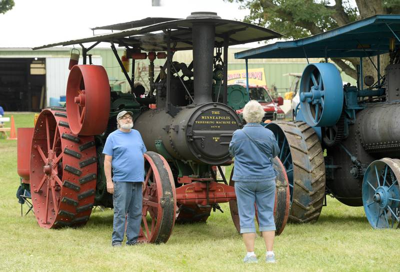 Ginny Neal, right takes a photo of Chris Guliuzza in front of a 1917 The Minneapolis steam tractor during the Annual Sycamore Steam Show in Sycamore on Friday, Aug. 12, 2022.