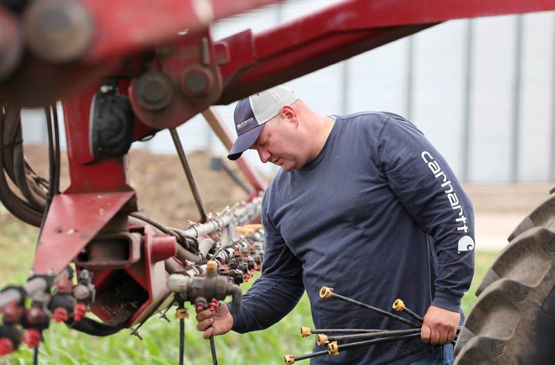 Farmer Mike Schweitzer changes the nozzles on the sprayer tractor in one of his fields Friday, June 16, 2023, on his farm in Malta.