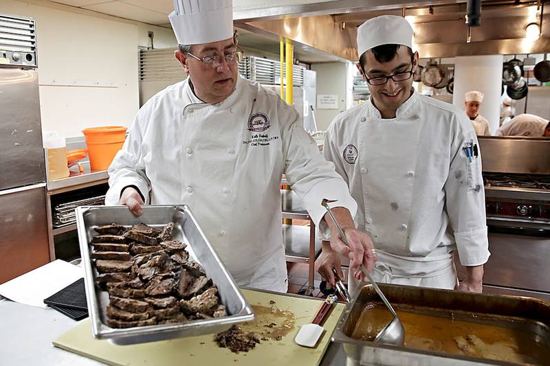 Chef Keith Vonhoff (left) instructs Joe Kotecki as Kotecki prepares sauerbraten at Joliet Junior College on April 8. Vonhoff is retiring in May after 30 years at the college.