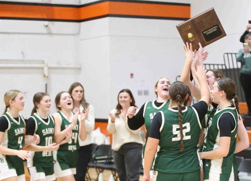 Members of the St. Bede Lady Bruin basketball team hoist  the Tri-County Conference championship trophy on Thursday, Jan. 23, 2025 at Roanoke-Benson High School.