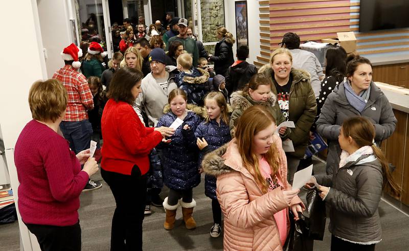 Children and their parents enter the library on Friday, Dec. 2, 2022, for the Very Merry Huntley Holiday Open House at the Huntley Area Public Library. The event featured musical entertainment by Andy Huber, reindeer, Santa, a scavenger hunt, face painting, and a snowball toss.