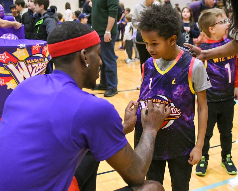 Jace Rice, 8, of Downers Grove gets an autograph from Harlem Wizard player Dragon on Sunday Jan. 19, 2025, before the start of the game held at Downers Grove South High School.