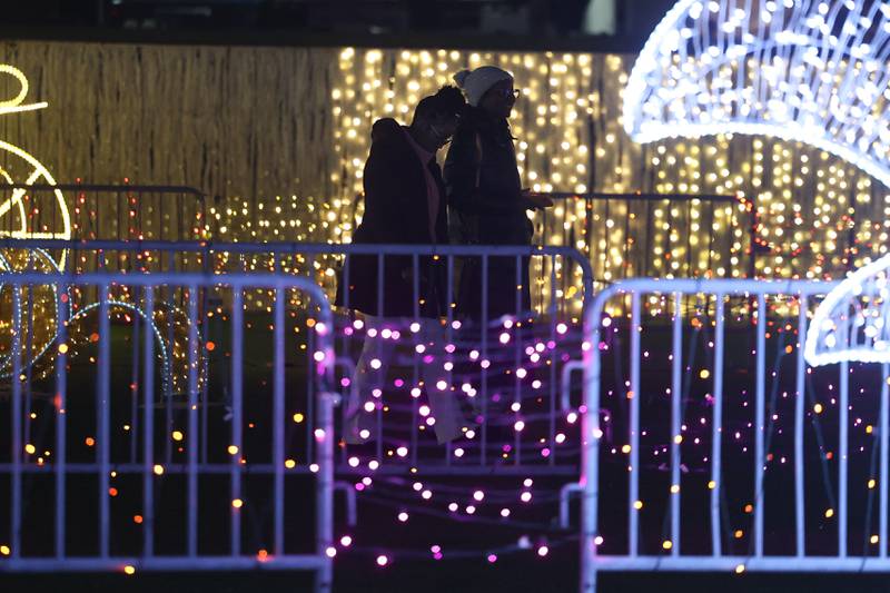 A couple walks through the lights at the GLOW Holiday Festival at Slammers Stadium on Wednesday, Nov. 27, 2024 in Joliet.