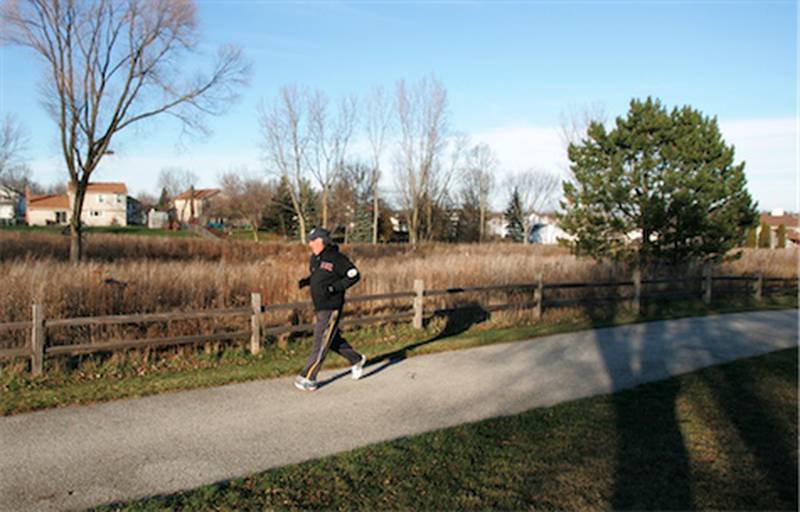 A man jogs past the bird and butterfly sanctuary Wednesday at Gaslight Park in Algonquin. The village has received a conservation award from the U.S. Environmental Protection Agency for the sanctuary.