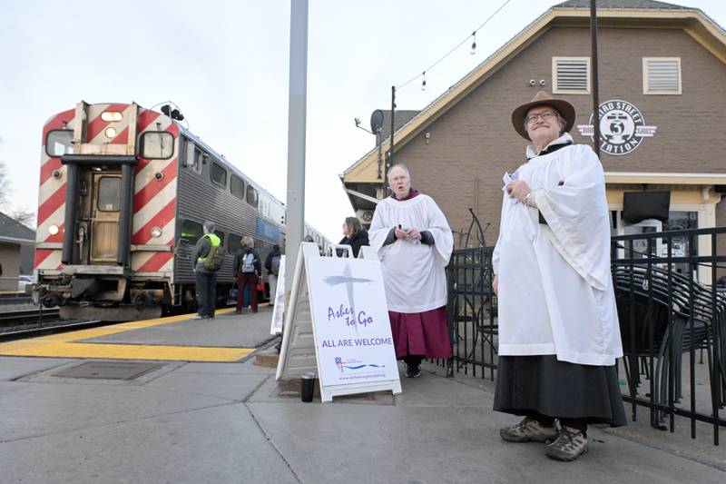 Bo Smith and Lee Kolodziej from St. Charles Episcopal Church administer ashes to the faithful on Ash Wednesday at the Geneva train station on Wednesday, Feb 18, 2026.