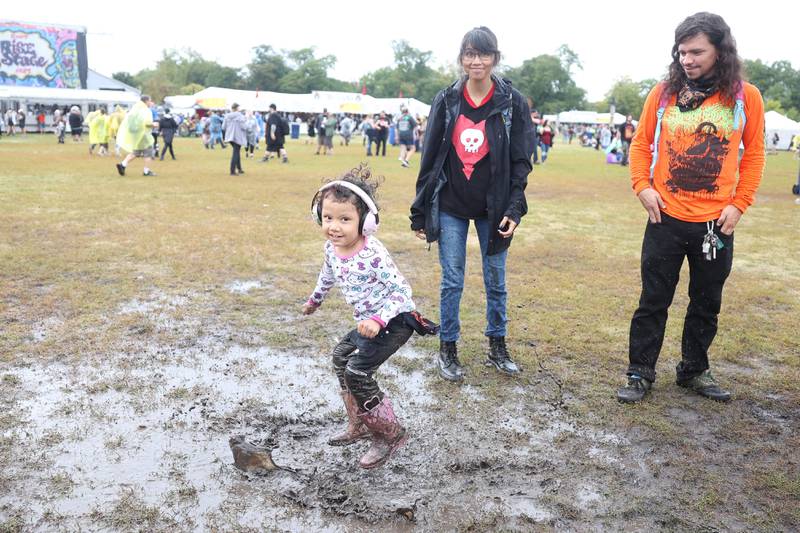 Andrew, left, and Jojo Meyer watch their daughter Anna dance in the mud at Riot Fest on Sunday, Sept. 22, 2024 in Chicago.