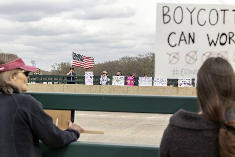 Protestors line the edges of the Galena Avenue bridge in Dixon Saturday, April 19, 2025, voicing their opinion of President Trump and their feelings the administration is not following a Democracy based government.