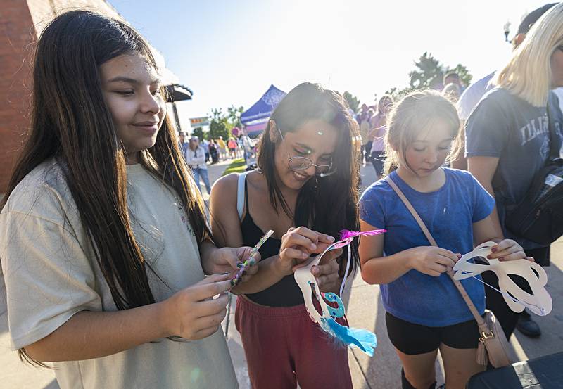 Liliana Ocampo (left), 12, Isabella Ocampo, 19, and Jayden Roberts, 11, work on making masks Saturday, Aug. 10, 2024 at Dixon’s Venetian Night.