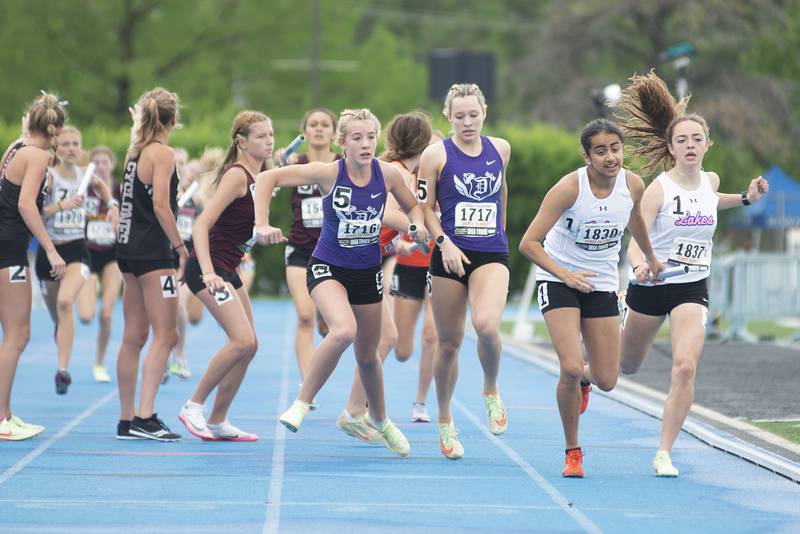 Dixon's Emma Smith (left) takes the baton from Hannah Steinmeyer during the 2A 4x8 finals during the IHSA girls state championships, Saturday, May 21, 2022 in Charleston.