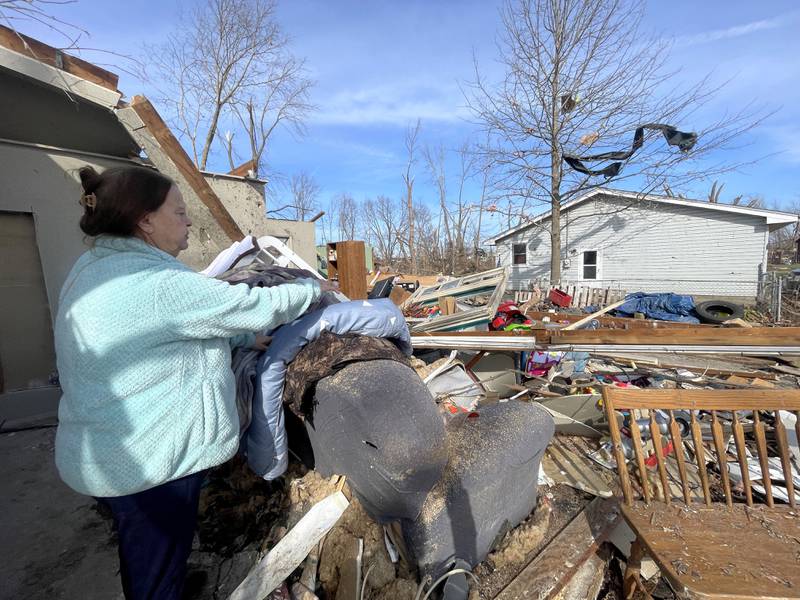 Aroma Park resident Patricia Kime stands in what was her living room at her home on Strasma North Drive, which was destroyed by the March 10 EF-3 tornado. The bathroom she took shelter in was the only intact room in the house, she said.