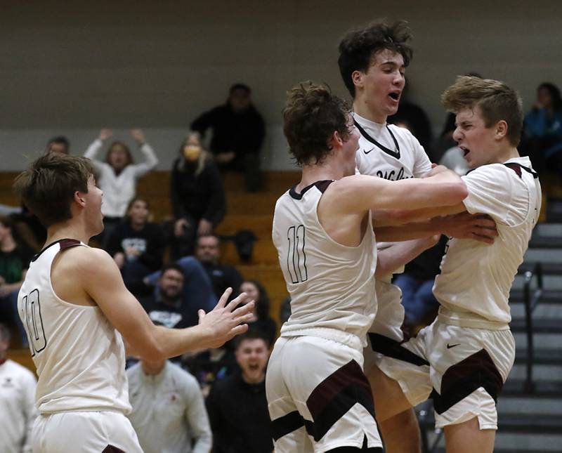 Prairie Ridge's Drake Tomasiewicz is mugged by his teammates, Cade Collins, James Muse and Ben Gablenz after Tomasiewicz made the game winning basket to defeat Woodstock North in a IHSA Class 3A boys basketball regional boys basketball game Thursday, Feb. 23, 2023, at Woodstock High School.