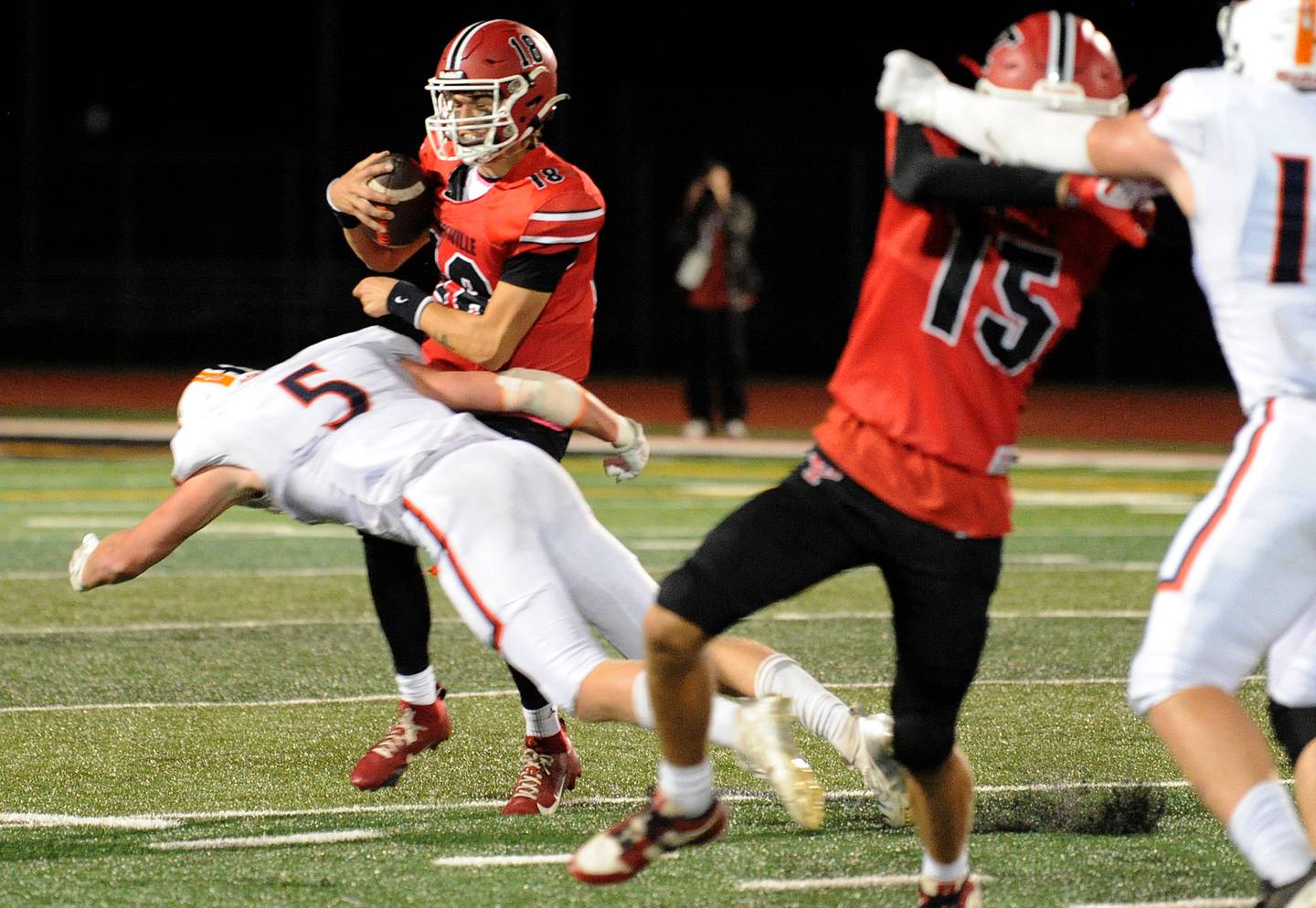 Oswego defender Carson Cooney (5) blasts through for a sack on Yorkville quarterback Jack Beetham (18) on Friday, Oct. 11, 2024, at Yorkville High School.
