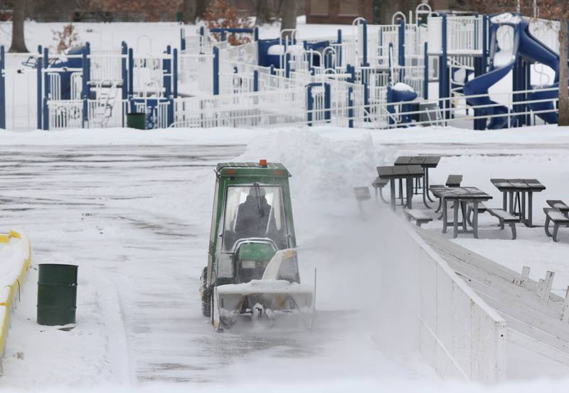 A DeKalb Park District employee clears snow from the parking lot and ice rink near the playground Wednesday, Feb. 2, 2022, at Hopkins Park in DeKalb. Snow fell overnight and into Wednesday across DeKalb County.