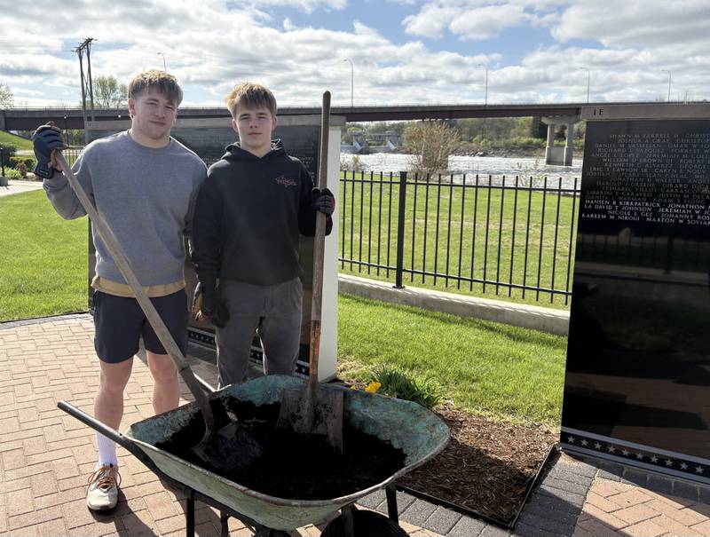 Marquette High School students and Future Farmers of America members Reily Leifheit and Koby Clark pose for a photo while volunteering to help lock sand into the paver sidewalk Saturday, April 25, at the Middle East Conflicts Wall Memorial in Marseilles.