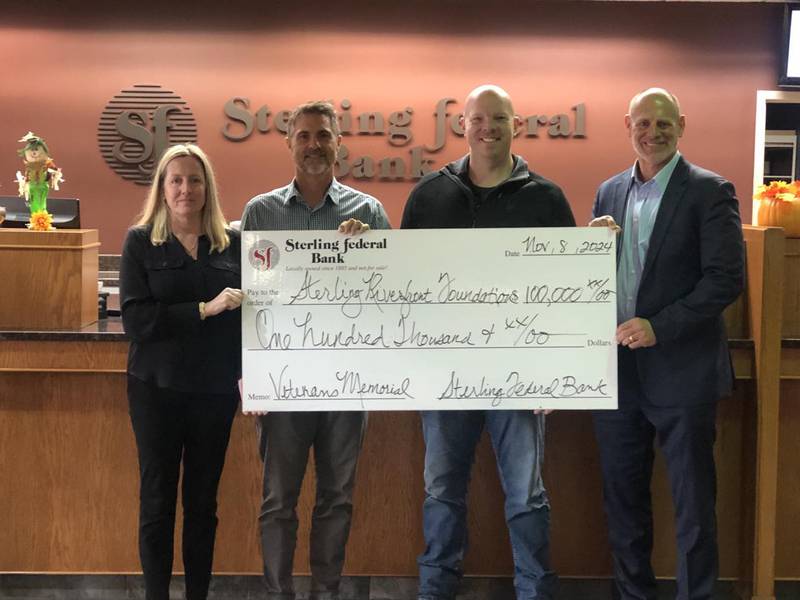 Dean Ahlers, president of Sterling Federal Bank, presents a $100,000 check to Heather Sotelo, Terry McGuire and Josh Johnson.