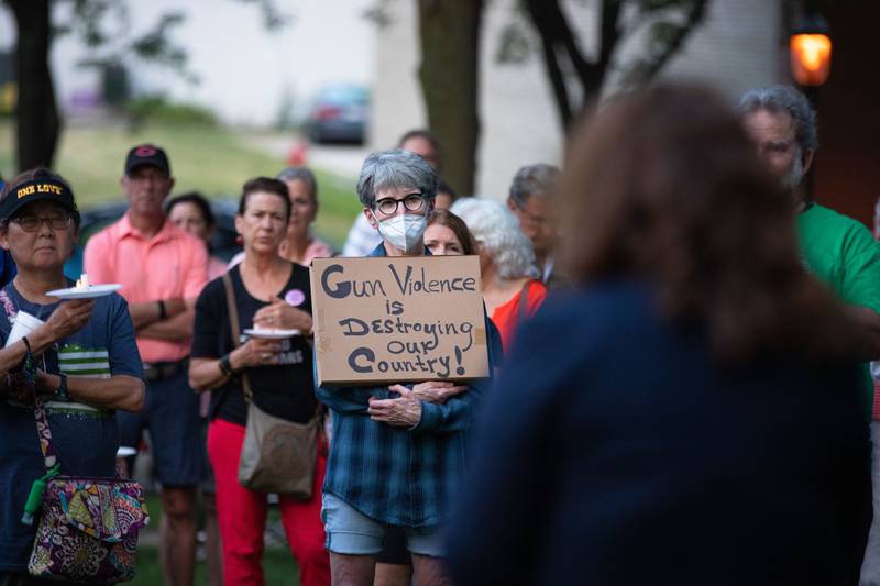 Roxanne Curtis of Batavia holds a sign during a candlelight vigil at the Kane County Courthouse in Geneva on Wednesday, July 6, 2022. The vigil was organized to honor the mass shooting at a Fourth of July Parade in Highland Park.