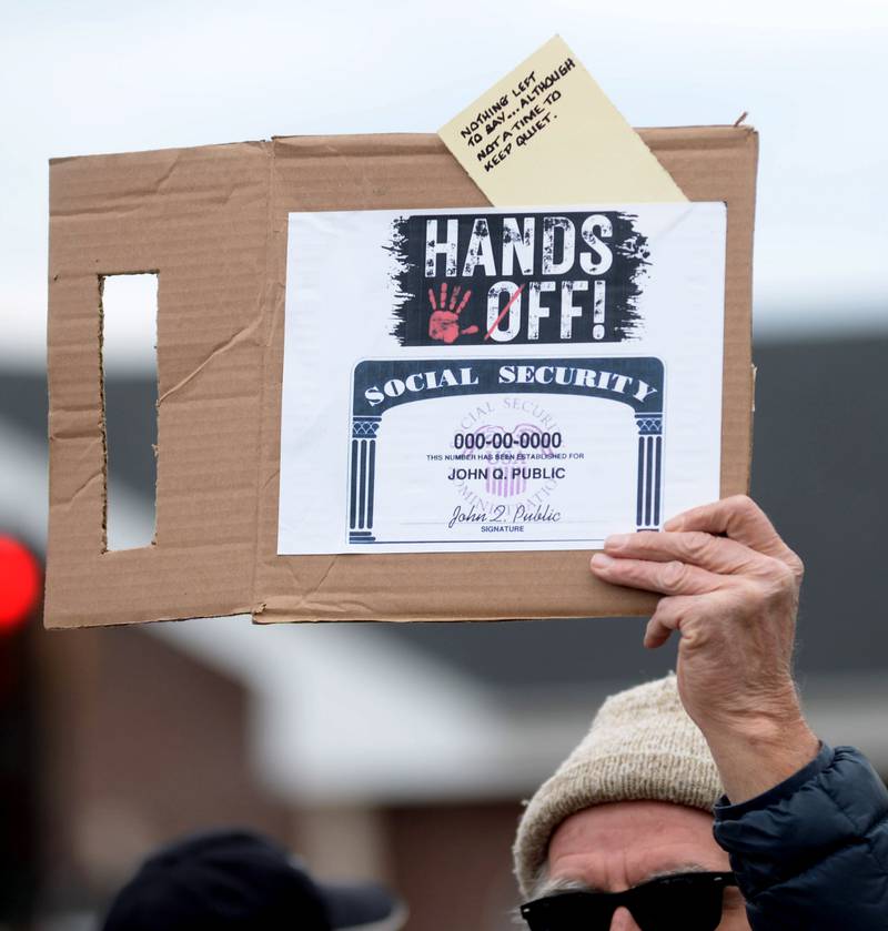 A man holds a sign during the Hands Off demonstration around the historic Ogle County Courthouse in Oregon on Saturday, April 5, 2025. Around 400 people attended the afternoon rally to show their dissatisfaction with decisions and actions by President Donald Trump.