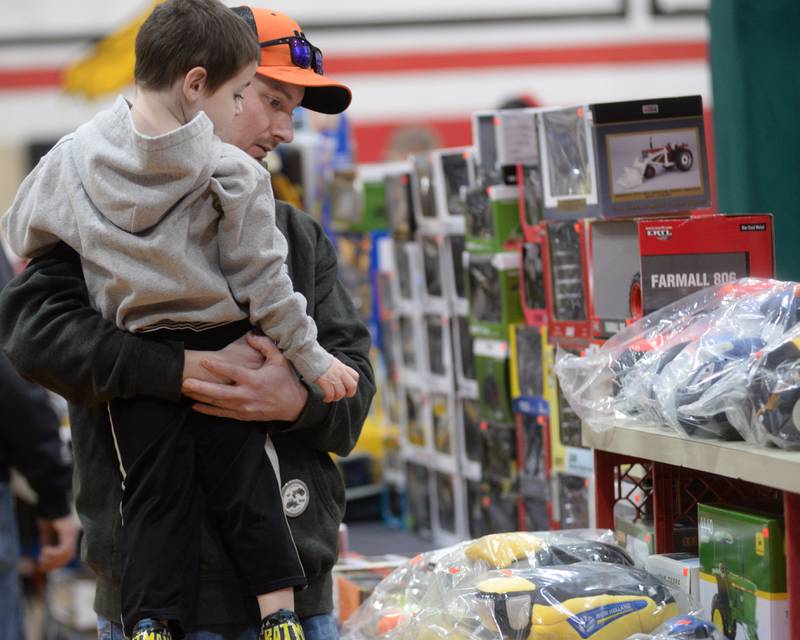 Brian Koeller holds Clay Beach, 3, of Forreston, as they look. over some of the items for sale at the Forreston FFA Alumni's Farm Toy and Craft Show on Saturday, March 8, 2025. The event was held at the Forreston High School.