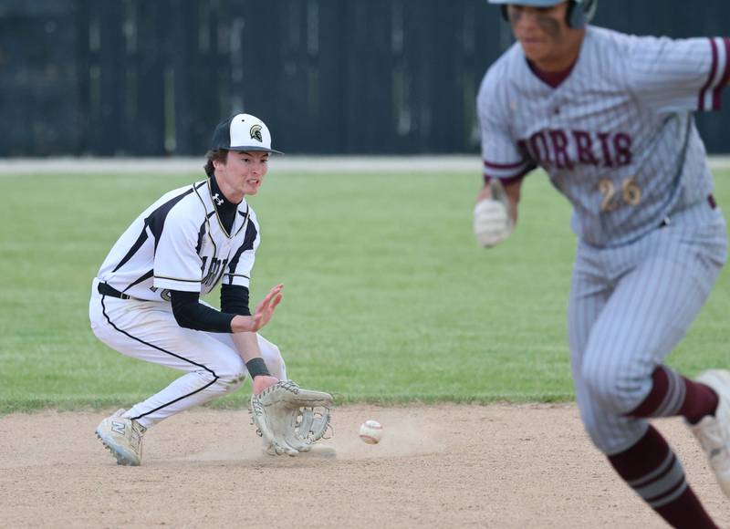 Sycamore's Jack Montani tries to field a grounder as Morris' Bryce Lee crosses in front of him Wednesday, May 13, 2026, during their game at the Sycamore Community Sports Complex.