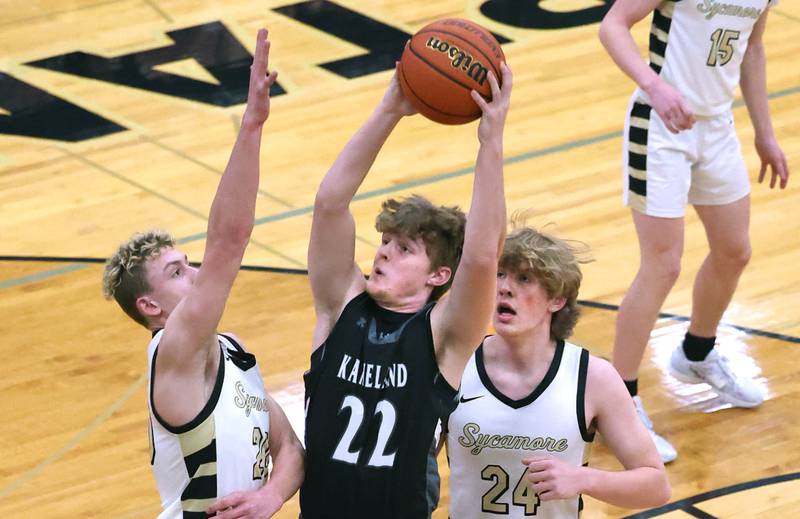 Kaneland's Johnny Spallasso shoots between Sycamore's Thatcher Friedrichs (left) and Lucas Winburn during their game Friday, Feb. 10, 2023, at Sycamore High School.