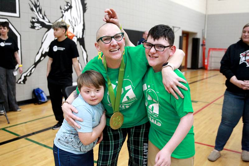 Martin Elementary School special education teacher Jennifer Slad embraces current student Harrison Shaw (left) and former student, Matthew Erickson, after her head was shaved at Marlowe Middle School in Huntley for a St. Baldrick’s Foundation fundraiser. Slad shaves her head in honor of Matthew, who is a cancer survivor.