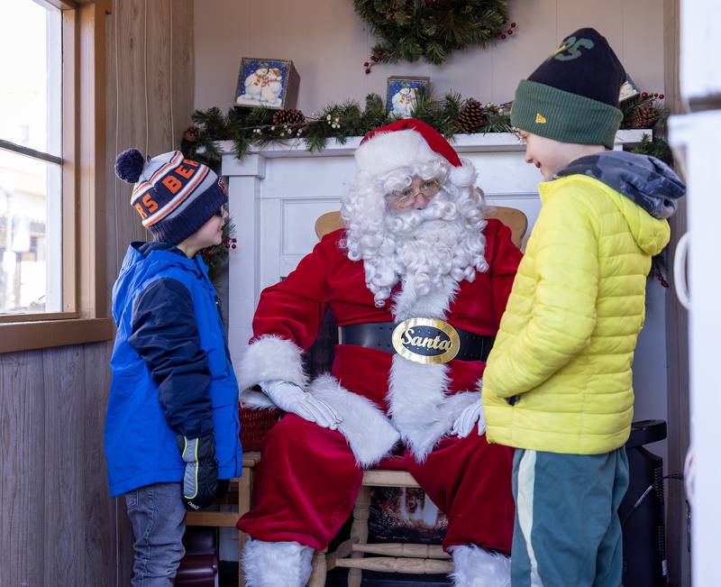 Brothers Josh, 5, (left) and Ryan Zacharski, 7, of Downers Grove talk with Santa Claus at the Gingerbread House in Downers Grove, Ill. on Sunday, Dec. 18, 2022.