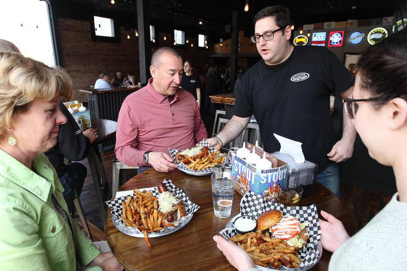 Richmond Brat Haus co-owner Tony Garbis serves Amy and Bob Rodriguez of Kansas City and their daughter Kelsey Rodriguez of Chicago during the lunch rush on Wednesday, April 12, 2017.