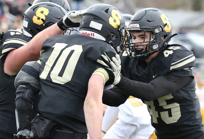 Sycamore's Zack Crawford (middle) celebrates with teammates after he scored a touchdown during their Class 5A state playoff game against Sterling Saturday, Nov. 12, 2022, at Sycamore High School.