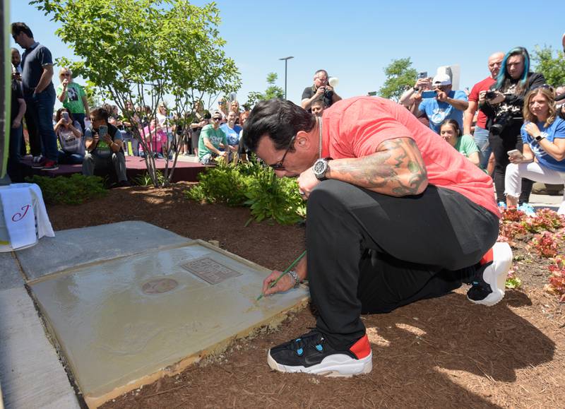 Danny Wood signs his name an places a hand print in wet cement during the Wahlk of Fame Ceremony for New Kids on the Block at the Wahlburgers in St. Charles on Saturday, June 18, 2022.