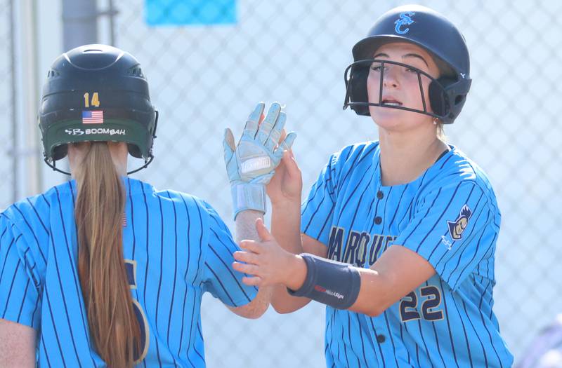 Marquette's Kinley Rick hi-fives teammate Chloe Thrush after scoring a run on Tuesday, April 23, 2026 at June Cross Field in Ottawa.