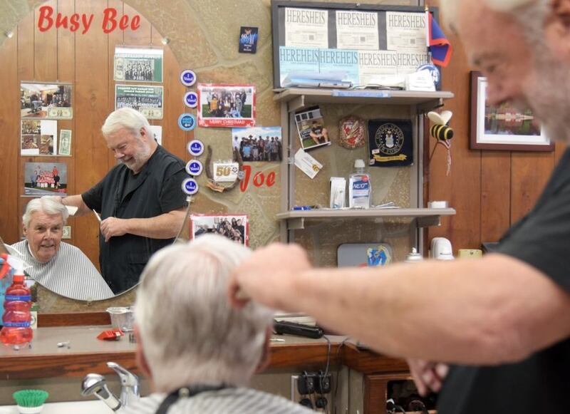 Busy Bee Barber Shop owner Joe Etheridge cuts the hair of Bill Gooch of Elmhurst. The Glen Ellyn shop has been in business for 100 years and Gooch is their longest continuous customer, first getting his haircut there in 1948. (Rick West | Staff Photographer)