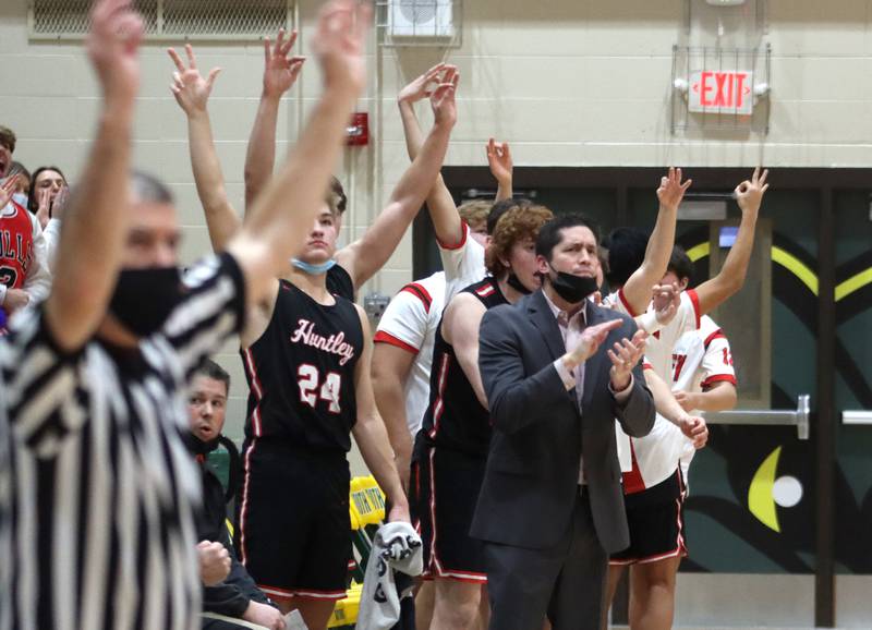 Huntley’s players and coaches celebrate a Red Raider three-point basket against Crystal Lake South in boys varsity basketball at Crystal Lake Friday night.