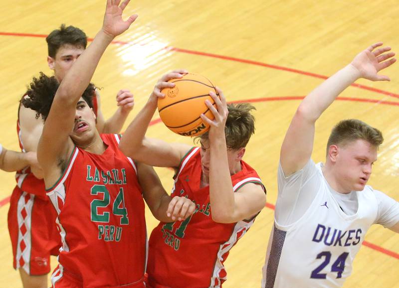 L-P's Jameson Hill (middle) and  Marion Persich grab a rebound as Dixon's Eli Davidson backs away during the Class 3A Regional semifinal game on Wednesday, Feb. 26, 2025 in Sellett Gymnasium at L-P High School.