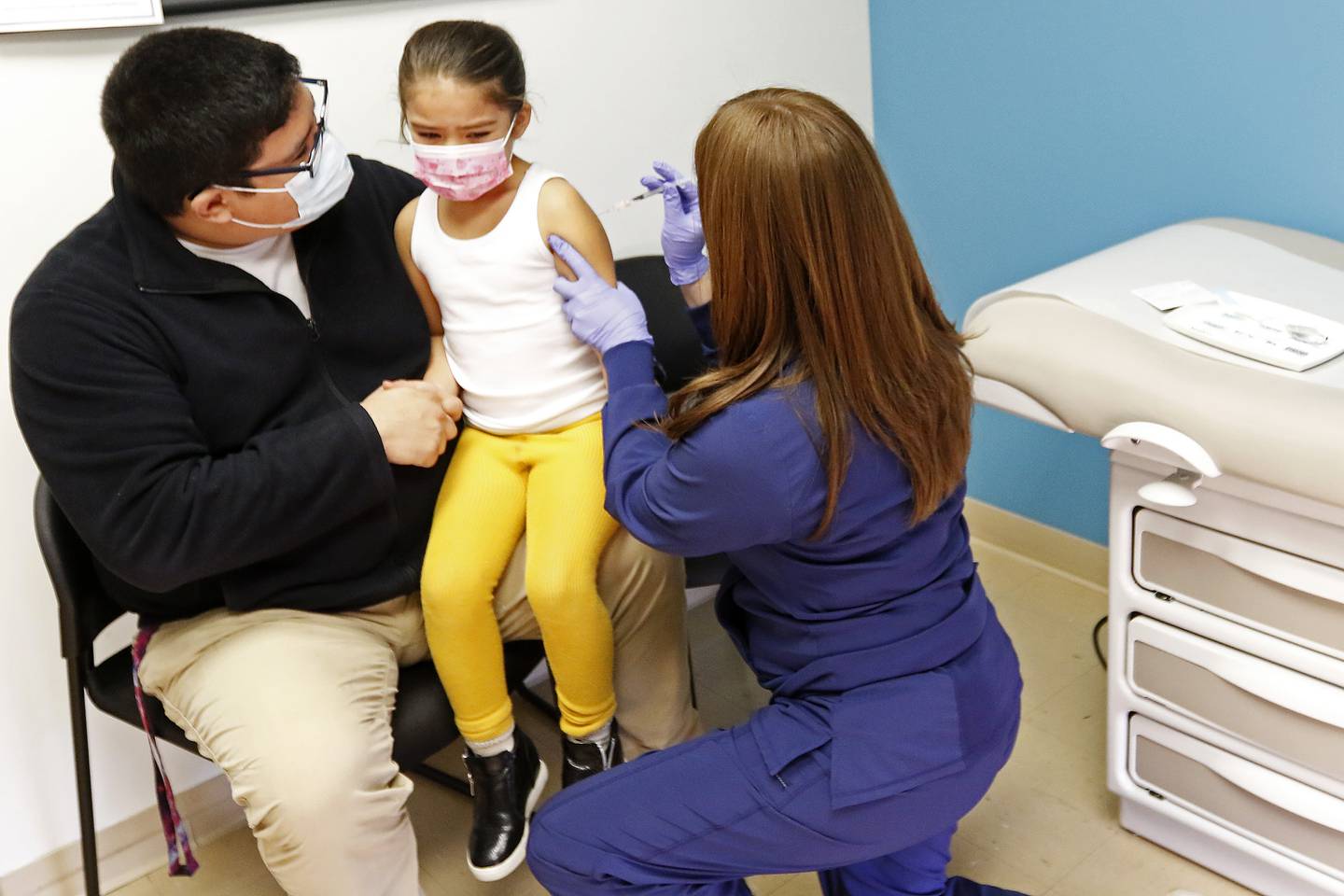 Brian Gomez, of Carpentersville, holds his daughter Eden, 5, as she gets her first dose of the Pfizer vaccine from nurse Maggie Juarez on Friday, Dec. 3, 2021, at Advocate Children's Medical Group in Crystal Lake.  Children ages 5 to 11 are now eligible for COVID-19 vaccines.