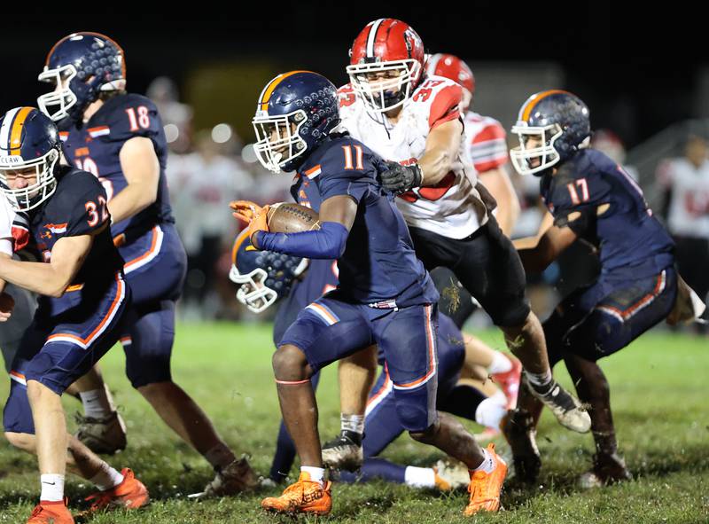Oswego’s Rodney Richardson (11) tries to escape the grasp of Yorkville’s Jacob Homerding (33) during the boys varsity football game on Friday, Oct. 6, 2023 in Oswego.