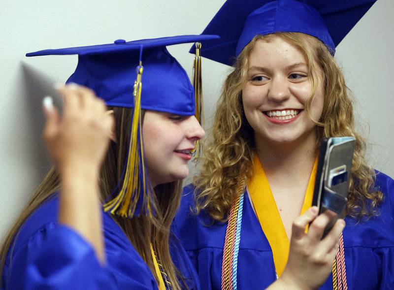 Wheaton North High School graduates Leah Baumhauer, left, and Katelyn Ables-Lyons share a laugh as they prepare for graduation ceremony Saturday, May 25, 2024 in the Physical Education Center of College of DuPage in Glen Ellyn.