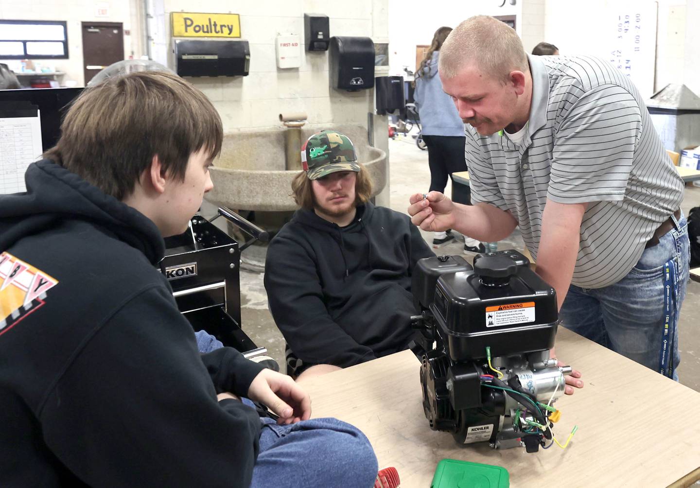 Sycamore High School agriculture teacher Christian Thurwanger looks at a piece of hardware as he helps sophomores Shawn Reser (left) and Ben Lancaster during a small engines lab Monday, March 14, 2022, at the school. The lab is part of the agriculture program in the Career and Technical Education department at Sycamore High School.