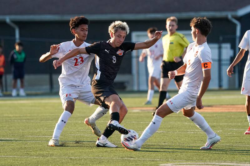 Wheaton Warrenville South's Max Barg (8) plays the ball between Oswego’s Alexander Nieves (23) and Dustin King (9) during a soccer match at Wheaton Warrenville South in Wheaton on Thursday, Aug 28, 2025.