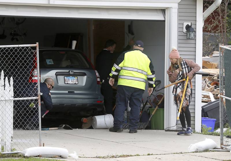 Firefighters helps Monica Diaz move tools and other things that were tossed around the car in her garage as her car is retrieved on Tuesday, October 10, 2023, after an explosion following a gas leak in the area leveled one home as caused several fires.