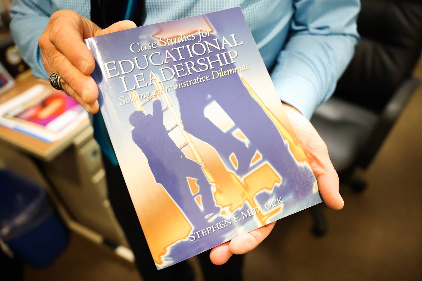 University of St. Francis professor Steve Midlock holds a copy of his book Case Studies for Educational Leadership on Friday, April 14, 2023 in Joliet.