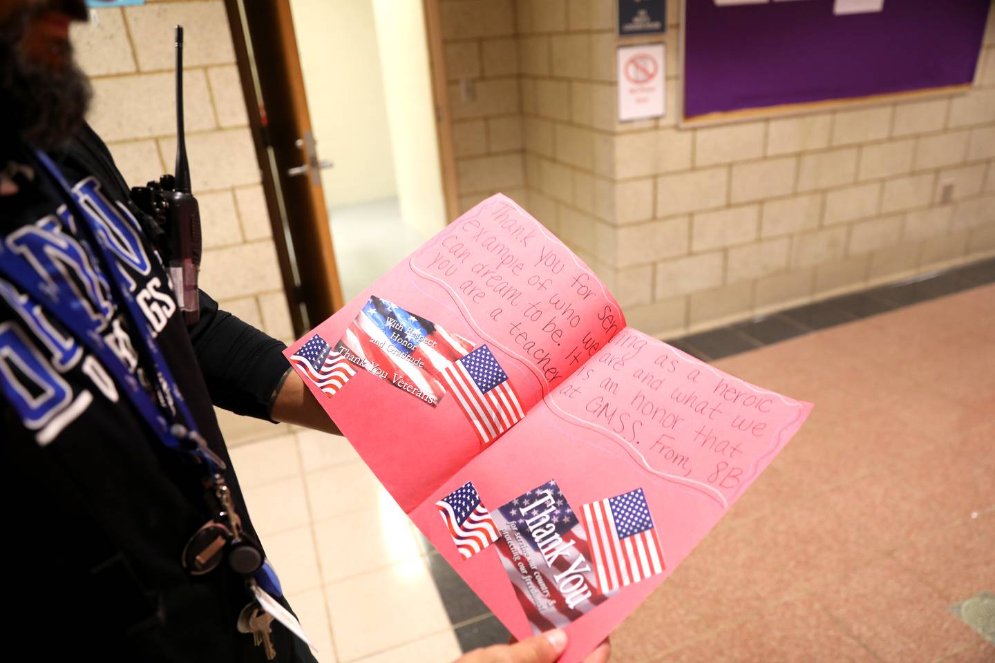 United States Air Force veteran and physical education teacher Garrett Lane shows one of the cards given to him by a Geneva Middle School South student.