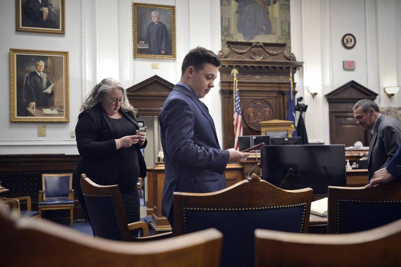 Defendant Kyle Rittenhouse checks his cell phone as he waits with his attorneys for the judge to relieve the jury during his trial at the Kenosha County Courthouse in Kenosha, Wis., on Thursday, Nov. 18, 2021. (Sean Krajacic/The Kenosha News via AP, Pool)