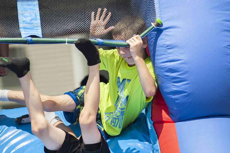 Tyler Butters, 8, wrestles a friend down the slide during the end of summer bash at the Coloma Homes in Rock Falls. Friday the residents will be able to cool down in the sprinklers and have a dinner of pizza provided by the Whiteside County House Authority.