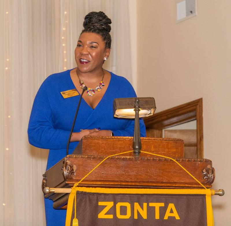 Zontian Essence Clark announces the upcoming LUNAFEST film festival to members of the audience at the Zonta Club of the Joliet Area “Magnificent Mardi Gras” event.
